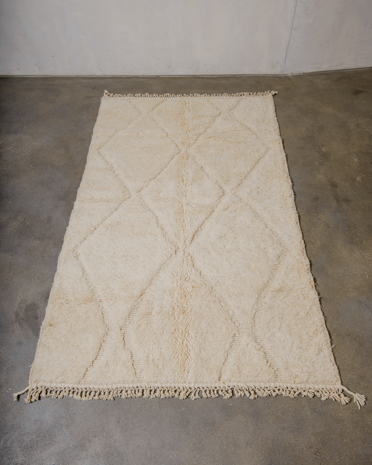 Beige diamond patterned rug on a concrete floor